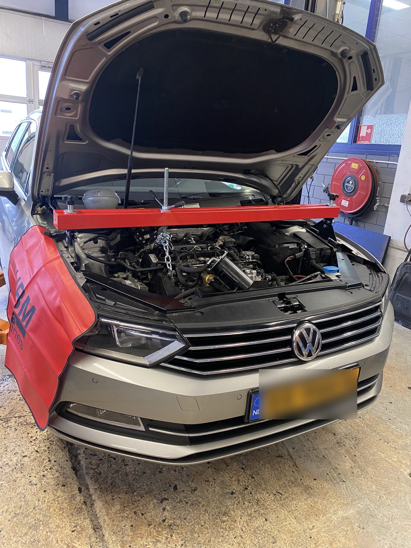 Een Volkswagen Passat met open motorkap in de werkplaats