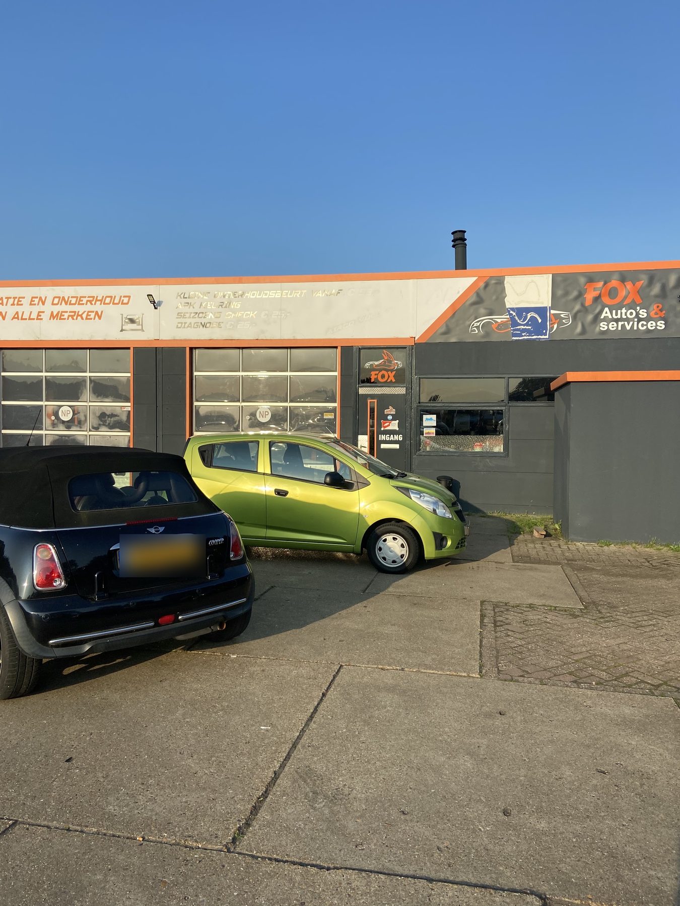 Voorzijde van de werkplaats met het FOX Auto's & services bord en de oranje deur